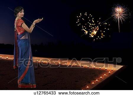 Stock Image - Portrait of a woman holding a diya. Fotosearch