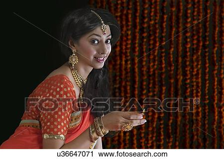 Stock Image - Portrait of a woman holding a diya. Fotosearch