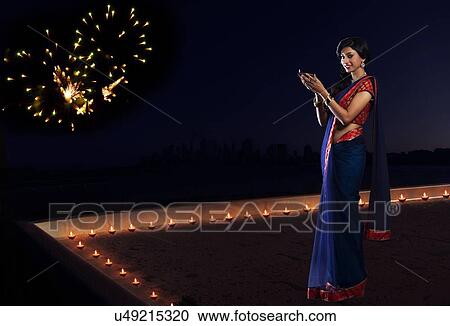 Stock Image - Portrait of a woman holding a diya. Fotosearch