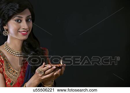 Stock Image - Portrait of a woman holding a diya. Fotosearch