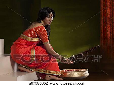 Stock Image - Portrait of a woman holding a diya. Fotosearch