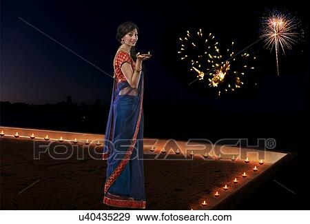 Stock Photo - Portrait of a woman holding a diya. Fotosearch