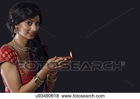 Portrait of a woman holding a diya View Large Photo Image Stock Photo - Portrait of a woman holding a diya. Fotosearch