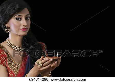 Stock Photograph - Portrait of a woman holding a diya. Fotosearch
