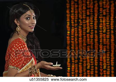 Stock Photography - Portrait of a woman holding a diya. Fotosearch