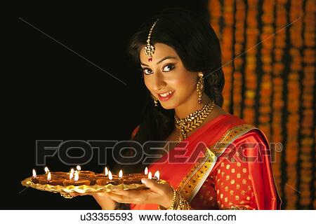 Stock Image - Portrait of a woman holding a tray of diyas. Fotosearch