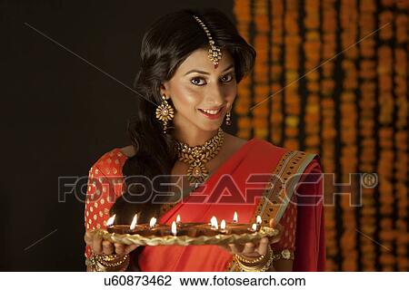 Stock Image - Portrait of a woman holding a tray of diyas. Fotosearch