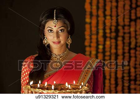 Portrait of a woman holding a tray of diyas View Large Photo Image Stock Image - Portrait of a woman holding a tray of diyas. Fotosearch