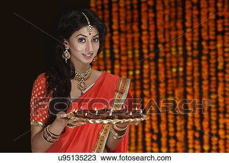 Portrait of a woman holding a tray of diyas View Large Photo Image Stock Image - Portrait of a woman holding a tray of diyas. Fotosearch