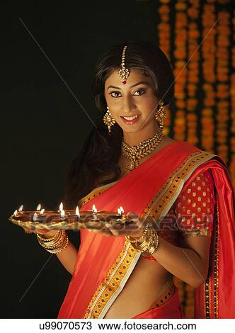 Stock Image - Portrait of a woman holding a tray of diyas. Fotosearch