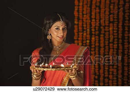 Stock Photo - Portrait of a woman holding a tray of diyas. Fotosearch