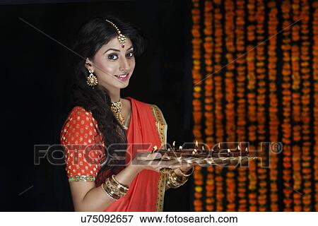 Stock Photo - Portrait of a woman holding a tray of diyas. Fotosearch
