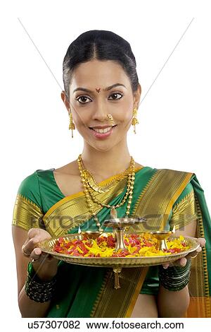 Stock Image - Portrait of a woman holding a tray with diyas . Fotosearch