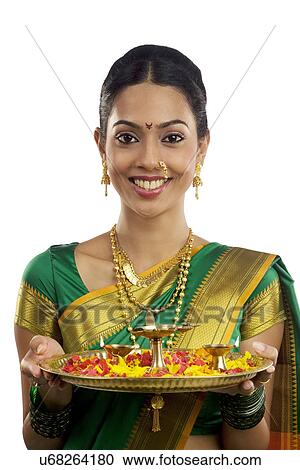Stock Image - Portrait of a woman holding a tray with diyas . Fotosearch