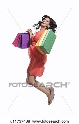 Stock Photo - Portrait of a woman jumping with shopping bags. Fotosearch