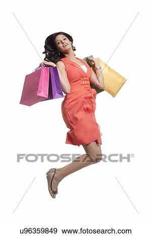 Portrait of a woman jumping with shopping bags View Large Photo Image Stock Photo - Portrait of a woman jumping with shopping bags. Fotosearch