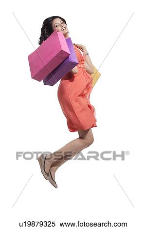 Stock Photography - Portrait of a woman jumping with shopping bags. Fotosearch