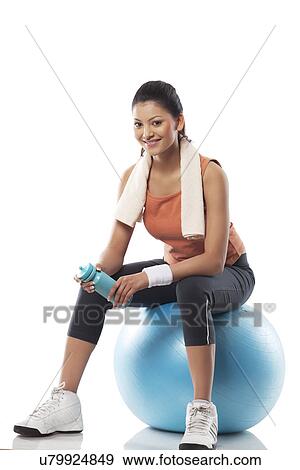 Stock Photo - Portrait of a woman sitting on a exercise ball . Fotosearch