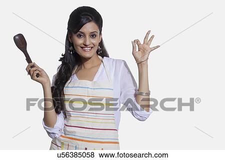 Portrait of a woman with a cooking utensil giving ok sign View Large Photo Image Stock Photo - Portrait of a woman with a cooking utensil giving ok sign. Fotosearch