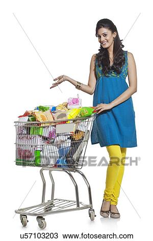Stock Image - Portrait of a woman with a shopping cart gesturing. Fotosearch