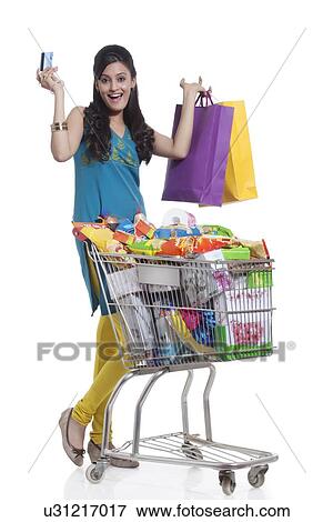 Stock Photo - Portrait of a woman with a shopping cart, shopping bags and credit card. Fotosearch