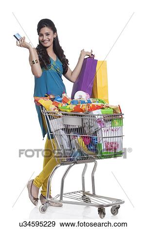 Stock Photo - Portrait of a woman with a shopping cart, shopping bags and credit card. Fotosearch