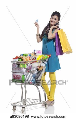Stock Photo - Portrait of a woman with a shopping cart, shopping bags and credit card. Fotosearch