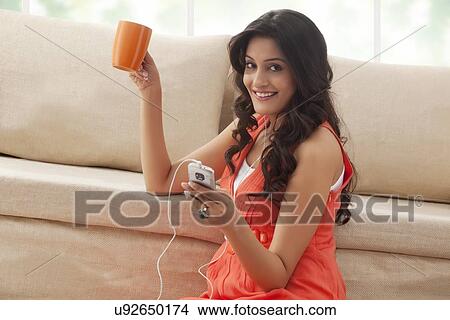 Picture - Portrait of a woman with coffee listening to music. Fotosearch