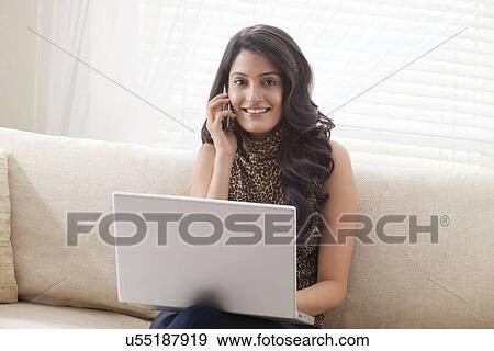 Portrait of a woman with laptop talking on mobile phone View Large Photo Image Stock Photo - Portrait of a woman with laptop talking on mobile phone. Fotosearch
