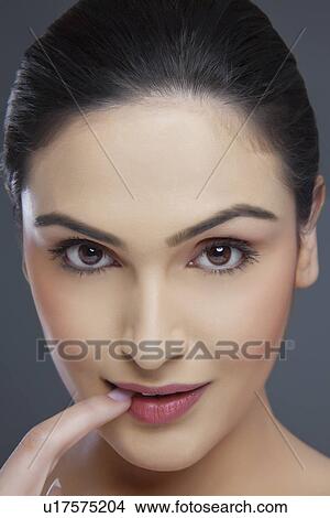 Portrait of a young female biting her fingernail over colored background View Large Photo Image Picture - Portrait of a young female biting her fingernail over colored background . Fotosearch