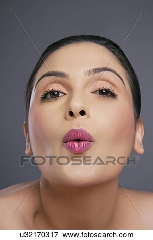 Portrait of a young female making a facial gesture over colored background View Large Photo Image Stock Photo - Portrait of a young female making a facial gesture over colored background . Fotosearch