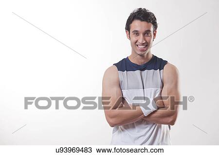 Stock Image - Portrait of a young fit man with arms crossed over white background . Fotosearch