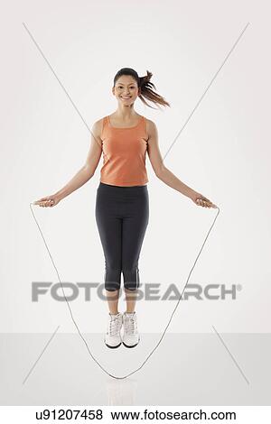 Stock Photo - Portrait of a young fit woman skipping over white background . Fotosearch