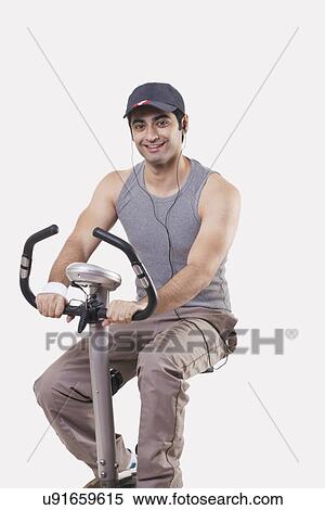 Portrait of a young man listening music while exercising over white background View Large Photo Image Stock Photography - Portrait of a young man listening music while exercising over white background . Fotosearch