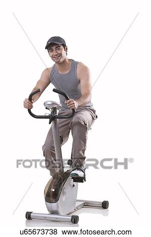 Portrait of a young man on exercise bike over white background View Large Photo Image Stock Photo - Portrait of a young man on exercise bike over white background . Fotosearch