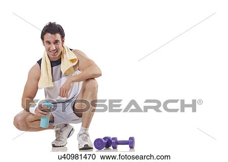 Portrait of a young man sitting next to a pair of dumbbell over white background View Large Photo Image Stock Image - Portrait of a young man sitting next to a pair of dumbbell over white background . Fotosearch