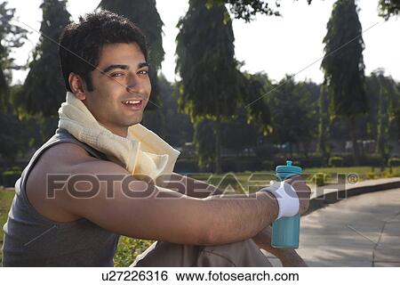 Stock Photograph - Portrait of a young man with towel round shoulders resting after sport activities . Fotosearch
