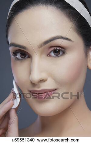 Portrait of a young woman cleansing her face over white background View Large Photo Image Stock Image - Portrait of a young woman cleansing her face over white background . Fotosearch