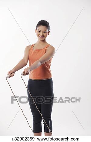 Portrait of a young woman with skipping rope over white background View Large Photo Image Stock Photo - Portrait of a young woman with skipping rope over white background . Fotosearch