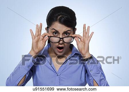 Portrait of amazed businesswoman looking over glasses against blue background View Large Photo Image Stock Photo - Portrait of amazed businesswoman looking over glasses against blue background. Fotosearch