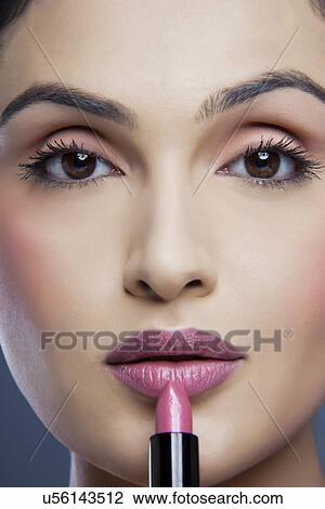 Portrait of an attractive female applying lipstick View Large Photo Image Stock Image - Portrait of an attractive female applying lipstick . Fotosearch