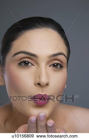Portrait of an attractive female blowing kiss over colored background View Large Photo Image Stock Photo - Portrait of an attractive female blowing kiss over colored background . Fotosearch