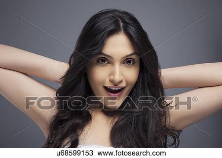 Stock Image - Portrait of an excited young female with long hair over colored background . Fotosearch