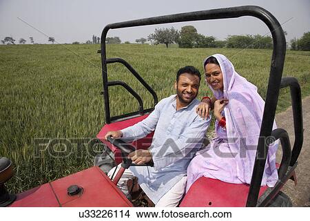 Portrait of an Indian couple sitting in a tractor with field in background View Large Photo Image Picture - Portrait of an Indian couple sitting in a tractor with field in background . Fotosearch
