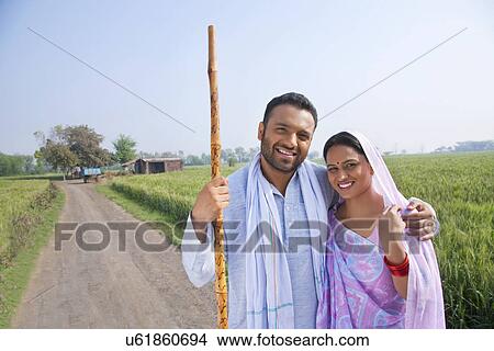 Picture - Portrait of an Indian couple smiling with field in background . Fotosearch
