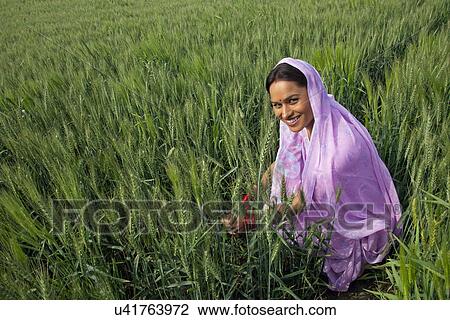 Stock Image - Portrait of an Indian female farm worker working in the field . Fotosearch