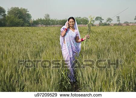 Portrait of an Indian female worker talking on phone while walking in the field View Large Photo Image Stock Photo - Portrait of an Indian female worker talking on phone while walking in the field . Fotosearch