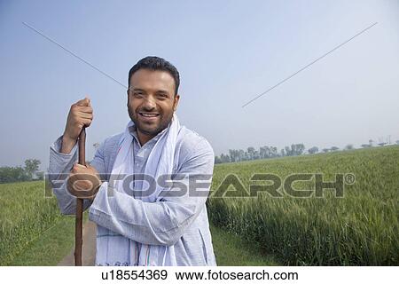 Portrait of an Indian man looking away while holding a stick View Large Photo Image Stock Photo - Portrait of an Indian man looking away while holding a stick . Fotosearch