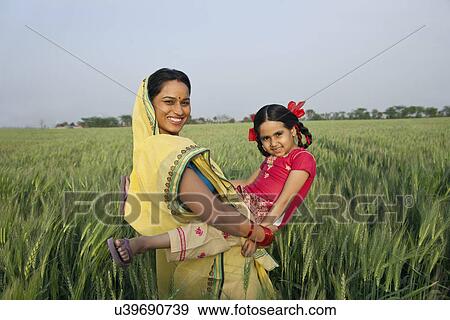 Stock Photo - Portrait of an Indian mother playing with her daughter in the field . Fotosearch