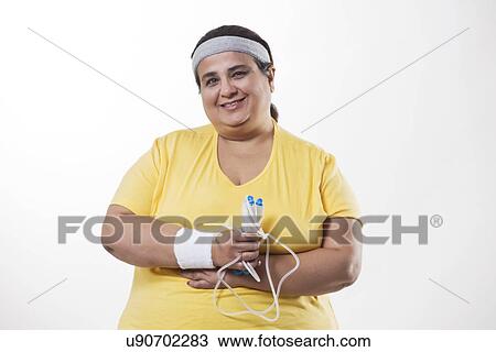 Stock Image - Portrait of an obese female with skipping rope over white background . Fotosearch